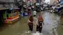 Banjir rob di kawasan Muara Baru Jakarta merupakan fenomena yang terjadi akibat pasang tinggi air laut yang bersamaan dengan kondisi cuaca tertentu. Tampak dalam foto, dua siswi mengarungi jalan yang terendam banjir akibat pasang tinggi di Muara Baru, Jakarta, pada Sabtu 6 Desember 2025. (ADITYA IRAWAN/AFP)