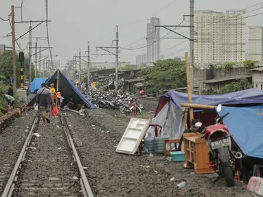 Pengungsi banjir mendirikan tenda di jalur rel kereta commuterline Tangerang-Duri di Kembangan Baru, Jakarta, Jumat (3/1/2020). Jalur rel yang nonaktif sementara karena banjir dimanfaatkan warga sekitar untuk mendirikan tenda darurat karena rumah mereka masih terendam. (Liputan6.com/Faizal Fanani)