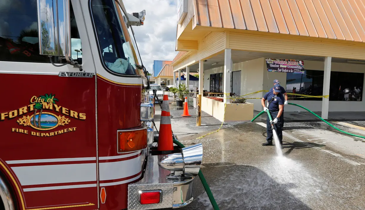Petugas pemadam membersihkan noda darah di lokasi penembakan di tempat parkir Club Blu di Fort Myers, Florida, Senin (25/7). Pria bersenjata melepaskan tembakan ke arah kerumunan orang yang berada di tempat parkiran klub malam itu. (REUTERS/Joe Skipper)