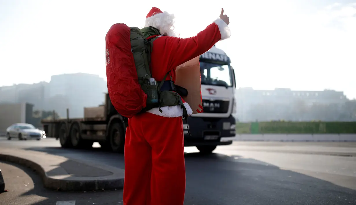 Seorang petualang asal Prancis, Remi Le Calvez mencari tumpangan dengan mengenakan kostum Santa Claus di Paris, Prancis, Selasa (6/12). Remi adalah seorang mantan pengusaha yang menjual asetnya dan memutuskan pergi keliling dunia.(Reuters/Benoit Tessier) 