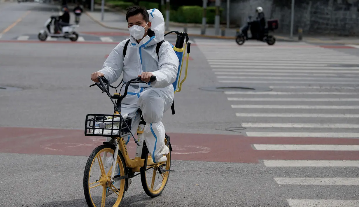 <p>Seorang pria yang mengenakan pakaian pelindung diri (APD) mengendarai sepeda di sepanjang jalan yang sepi di Beijing, China, Senin (9/5/2022). Jutaan orang di Beijing tinggal di rumah pada 9 Mei ketika ibu kota China mencoba untuk menangkis Covid -19 wabah dengan pembatasan ruang gerak. (Noel Celis / AFP )</p>