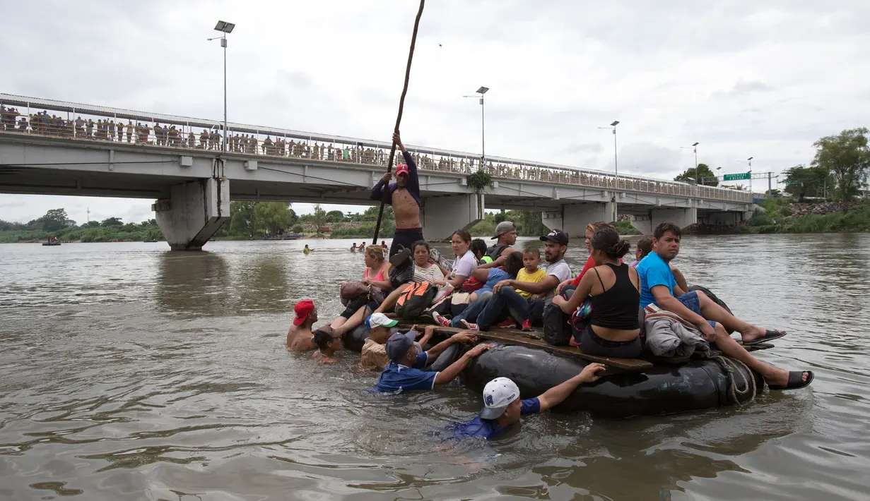 Rombongan imigran Honduras menyeberangi Sungai Suchiate menggunakan rakit dari ban di perbatasan antara Guatemala dan Meksiko di Ciudad Hidalgo, Meksiko, 20 Oktober 2018. Imigran Honduras menuju AS lewat Guatemala dan Meksiko. (AP Photo/Moises Castillo)