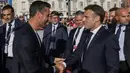 Presiden Prancis, Emanuel Macron (kanan) berjabat tangan dengan Presiden Komite Penyelenggara Olimpiade dan Paralimpiade Paris 2024 (Cojo) Tony Estanguet saat upacara penyambutan kedatangan api Olimpiade dan Paralimpiade Paris 2024 di Vieux-Port (Pelabuhan Tua) Marseille, Pranci, Rabu (08/05/2024) waktu setempat. (AFP/Pool/Ludovic Marin)
