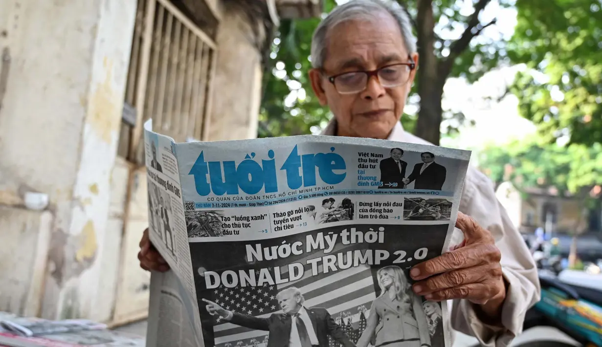 Donald Trump terpilih sebagai presiden ke-47 Amerika Serikat usai memenangi Pilpres AS 2024, Rabu (6/11/2024). Tampak dalam foto, seorang pria membaca koran Vietnam di Hanoi pada 7 November 2024, yang menunjukkan reaksi atas terpilihnya kembali Presiden AS terpilih Donald Trump. (Nhac NGUYEN/AFP)