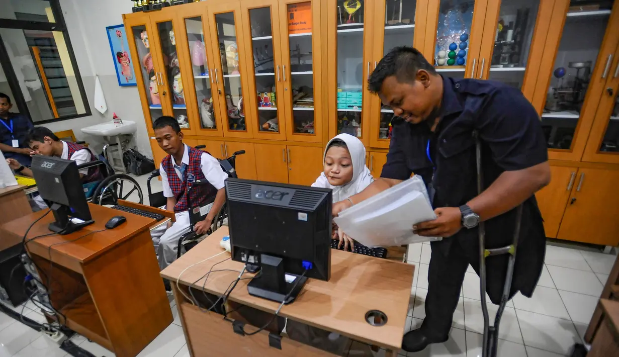 Berjalan dengan menggunakan tongkat besi, matanya terus menatap monitor-monitor komputer anak didik. Sesekali ia menghampiri komputer anak didik yang nampak kesulitan mengolah foto. Dengan penuh kesabaran, ia memberikan instruksi tahap demi tahap kepada beberapa muridnya yang menggunakan kursi roda yang juga mengalami celebral palsy (penurunan fungsi otak. (merdeka.com/Arie Basuki)