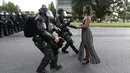 Polisi Anti Huru Hara AS bergegas menangkap seorang wanita yang melakukan unjuk rasa di dekat markas Kepolisian Rouge Baton di Baton Rouge, Louisiana, AS (9/7). Aksi tersebut sebagai kritik terkait kebrutalan polisi di AS. (REUTERS / Jonathan Bachman)