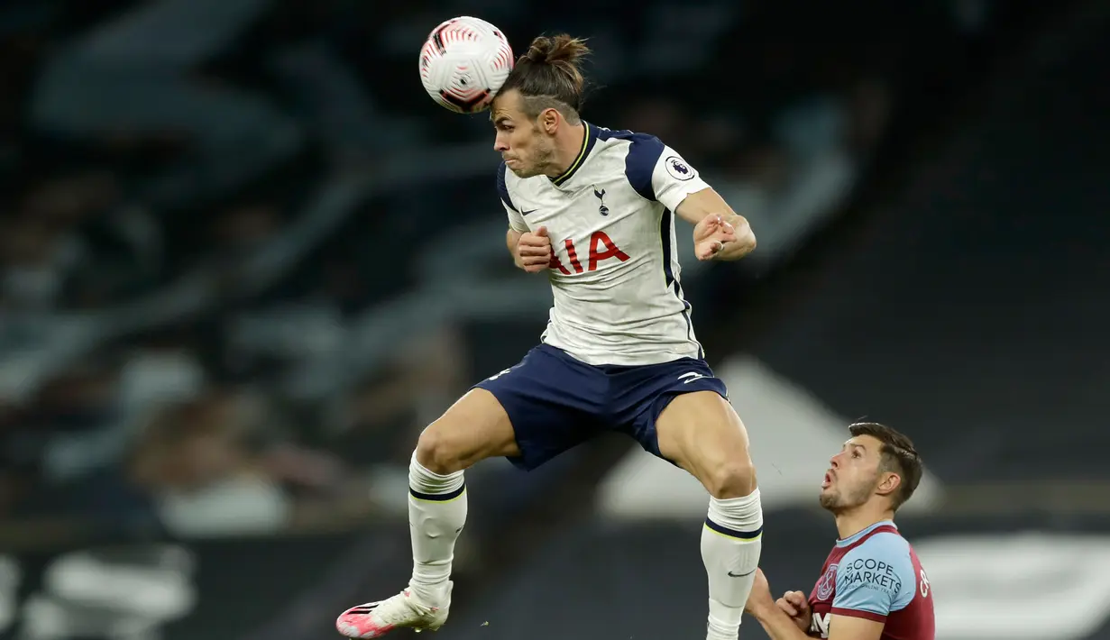 Penyerang Tottenham Hotspur, Gareth Bale menyundul bola di sebelah pemain West Ham, Aaron Cresswell dalam laga Liga Inggris di Tottenham Hotspur Stadium, Minggu (18/10/2020). Laga yang berakhir dramatis 3-3 itu diwarnai debut bintang anyar Tottenham, Gareth Bale. (AP photo/Matt Dunham, Pool)