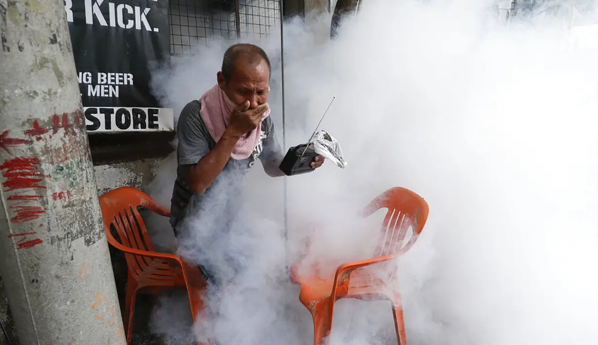 Warga memegang hidung dan radio portabelnya saat mencoba menghindari disinfeksi di desanya sebagai pencegahan penyebaran COVID-19 di Manila, Filipina, Senin (15/3/2021). Lonjakan kasus COVID-19 di Filipina menambah kekhawatiran atas lambannya vaksinasi dan keengganan publik. (AP Photo/Aaron Favila)