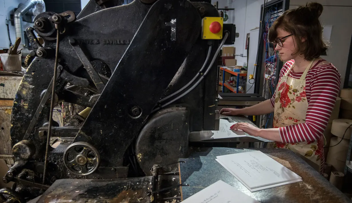 Lottie Small membuat undangan Pangeran Harry dan Meghan Markle menggunakan proses tradisional die-stamping, di bengkel perusahaan Barnard and Westwood, London, Kamis (22/3). Perusahaan ini sudah bekerja sama dengan Royal Family sejak 1985. (AP Photo)