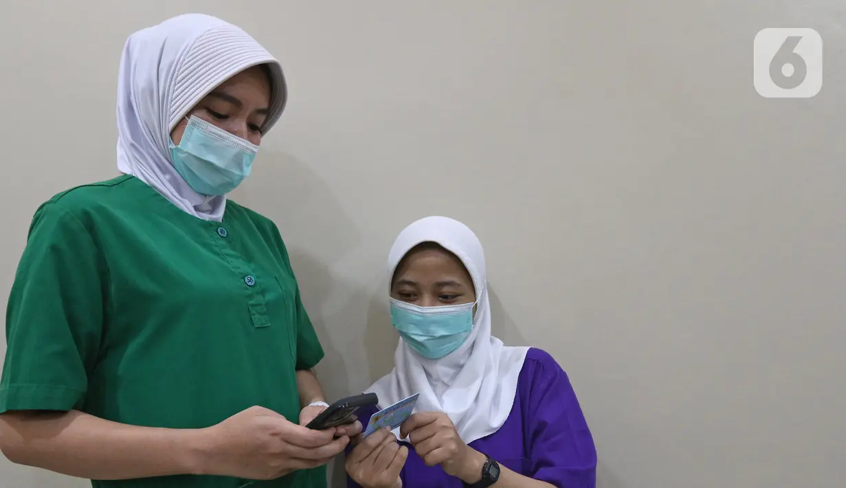 Tenaga kesehatan mengecek pesan singkat penerima vaksin COVID-19 di RSIA Tambak, Jakarta, Selasa (5/01/2021). Kementerian Kesehatan mengirimkan Short Message Service (SMS) blast secara serentak kepada penerima vaksin COVID-19 tahap pertama pada Kamis (31/12) lalu. (Liputan6.com/Herman Zakharia)