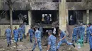 Puing-puing pesawat terlihat menghancurkan bagian dinding bangunan sekolah, merusak pagar besi, dan menciptakan lubang besar. (MUNIR UZ ZAMAN/AFP)