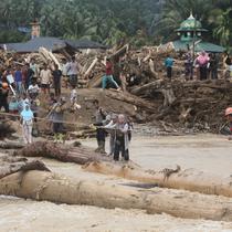 Warga yang menjadi korban banjir bandang di Batang Toru, Tapanuli Selatan, Sumatra Utara menggunakan kayu gelondongan untuk menyeberangi sungai, Selasa 2 Desember 2025. Warga Batang Toru, Tapanuli Selatan, terpaksa menggunakan jembatan darurat yang terbuat dari gelondongan kayu untuk menyeberangi sungai setelah jembatan utama rusak akibat terjangan banjir bandang baru-baru ini. (AP Photo/Binsar Bakkara)
