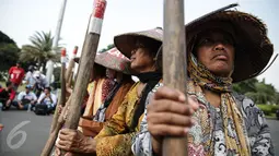 Sejumlah petani Pegunungan Kendeng menabuh lesung saat menggelar aksi di depan Istana Merdeka, Jakarta, Rabu (12/4). Mereka meminta Pemerintah untuk menghentikan pembangunan dan pabrik semen di Pegunungan Kendeng. (Liputan6.com/Faizal Fanani)