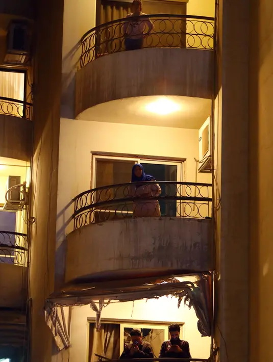 Orang-orang menyaksikan konser biola yang digelar dari atas balkon di Kairo, 31 Maret 2020. Setiap malam, pemain biola asal Mesir Mohammed Adel menampilkan konser langsung dari balkonnya untuk menghibur para tetangga selama jam malam nasional yang diberlakukan akibat COVID-19. (Xinhua/Ahmed Gomaa)