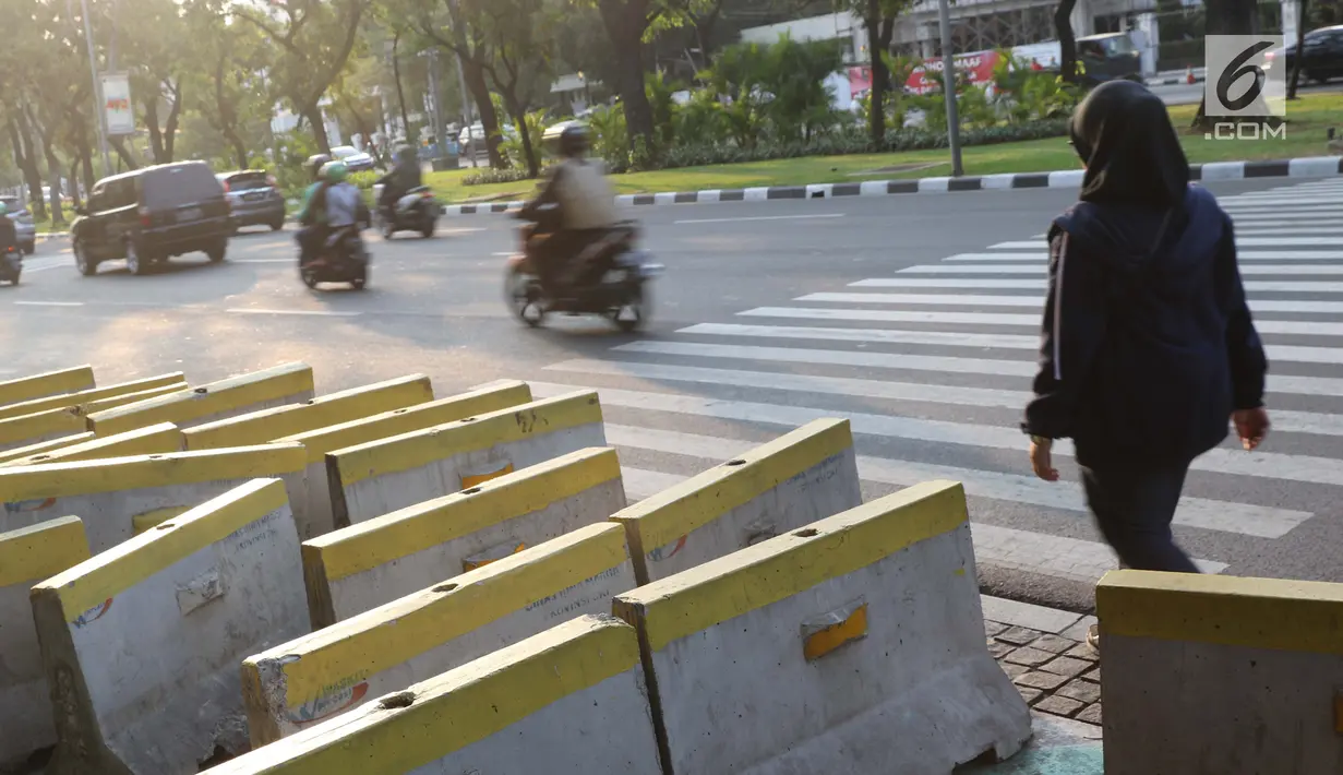 Pejalan kaki menghindari beton pembatas jalan yang diletakkan di atas trotoar Jalan Medan Merdeka Utara, Jakarta, Kamis (25/7/2019). Pembatas jalan yang berada tidak pada tempatnya mengganggu kenyamanan pejalan kaki yang melintasi trotoar jalan tersebut. (Liputan6.com/Helmi Fithriansyah)