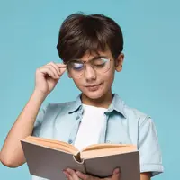 Seorang anak laki-laki sedang memegang kacamata sambil membaca buku (Foto Dok: Freepik/freepik).
