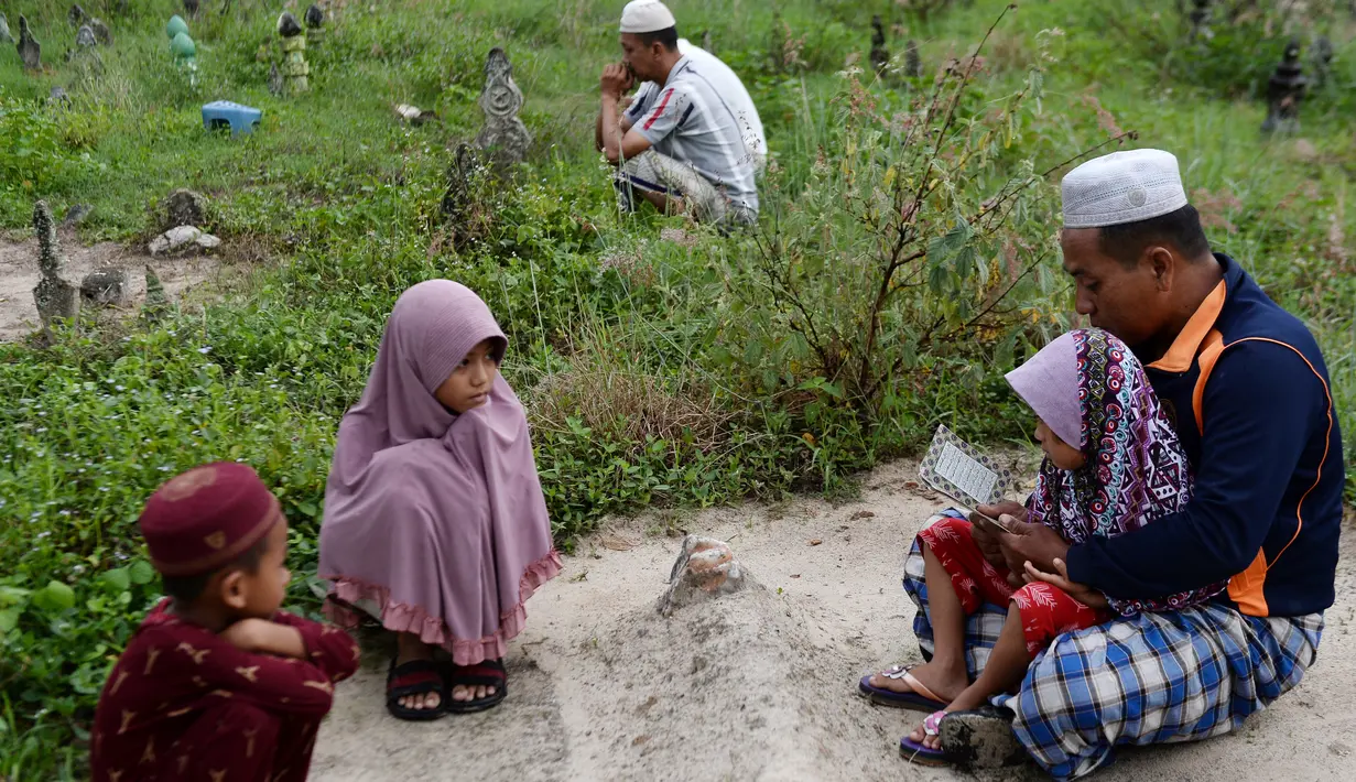 Seorang pria memanjatkan doa di makam kerabatnya saat Idul Fitri di Provinsi Narathiwat, Thailand, Rabu (5/6/2019). Tradisi ziarah kubur saat Idul Fitri ini mirip dengan apa yang biasa dilakukan muslim di Indonesia. (MADAREE TOHLALA/AFP)
