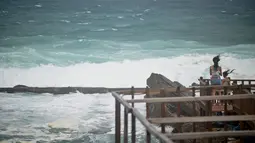 Orang-orang menyaksikan ombak di sepanjang pantai timur laut di New Taipei City saat Topan Hinnamnor mendekati Taiwan timur (3/9/2022). Badai itu membawa angin berkelanjutan maksimum 173 kilometer per jam, dengan hembusan hingga 209 kilometer per jam. (AFP/Sam Yeh)