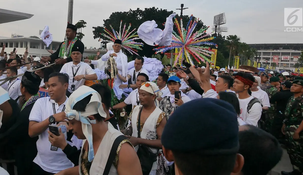 Cawapres 01 Ma'ruf Amin didampingi istrinye Nyai Wury Estu Handayani melempar kaus seusai 'Konser Putih Bersatu' di Stadion GBK, Jakarta, Sabtu (13/4). Pasangan Capres dan Cawapres 01 menggunakan kereta kencana seusai Konser Putih Bersatu menuju lokasi debat. (Liputan6.com/Herman Zakharia)