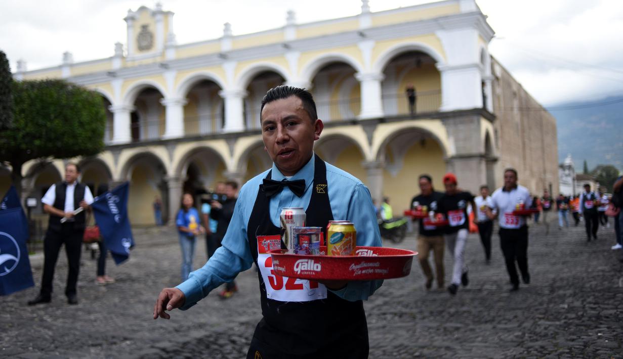 Seorang pramusaji membawa nampan dalam Waiters Race ke-16 di Antigua, barat daya Ibu Kota Guatemala City, Rabu (14/11). Ratusan peserta beradu kecepatan sembari membawa nampan berisi dua minuman ringan, bir dan air. (JOHAN ORDONEZ/AFP)
