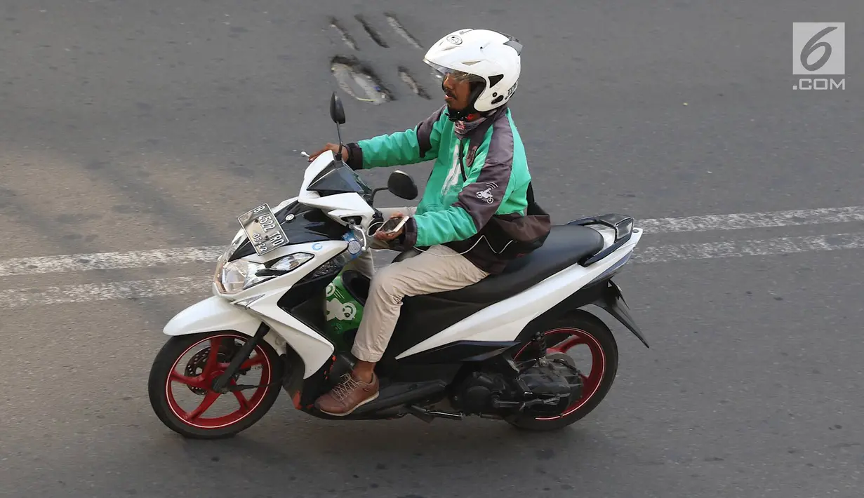 Pengendara sepeda motor mengoperasikan gawainya saat berkendara di Jakarta, Jumat (8/2). Mengoperasikan GPS saat mengemudi dinilai dapat mengganggu konsentrasi. (Liputan6.com/Immanuel Antonius)