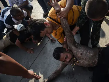 Dua orang pria kesurupan saat mengikuti festival tato suci di Biara Wat Bang Phra, Nakhon Pathom, Thailand (3/3). Festival tato suci tersebut festival tato suci festival yang digelar setiap tahunnya. (AFP Photo/Lillian Suwanrumpha)