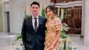 Berpose dengan sang suami, Chef Arnold, Tiffany Soetanto mengenakan long-ruffle dress bermotif floral bernuansa oranye. Menenteng handbag berwarna netral, Tiffany menyempurnakan penampilannya dengan tatanan rambut yang digelung. Foto: Instagram.