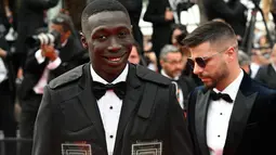 Influencer Italia Khaby Lame tiba untuk pemutaran film "Top Gun : Maverick" selama Festival Film Cannes edisi ke-75 di Cannes, Prancis selatan (18/5/2022). Khaby tampil dengan setelan jas dan kaca mata hitam. (AFP/Christophe Simon)