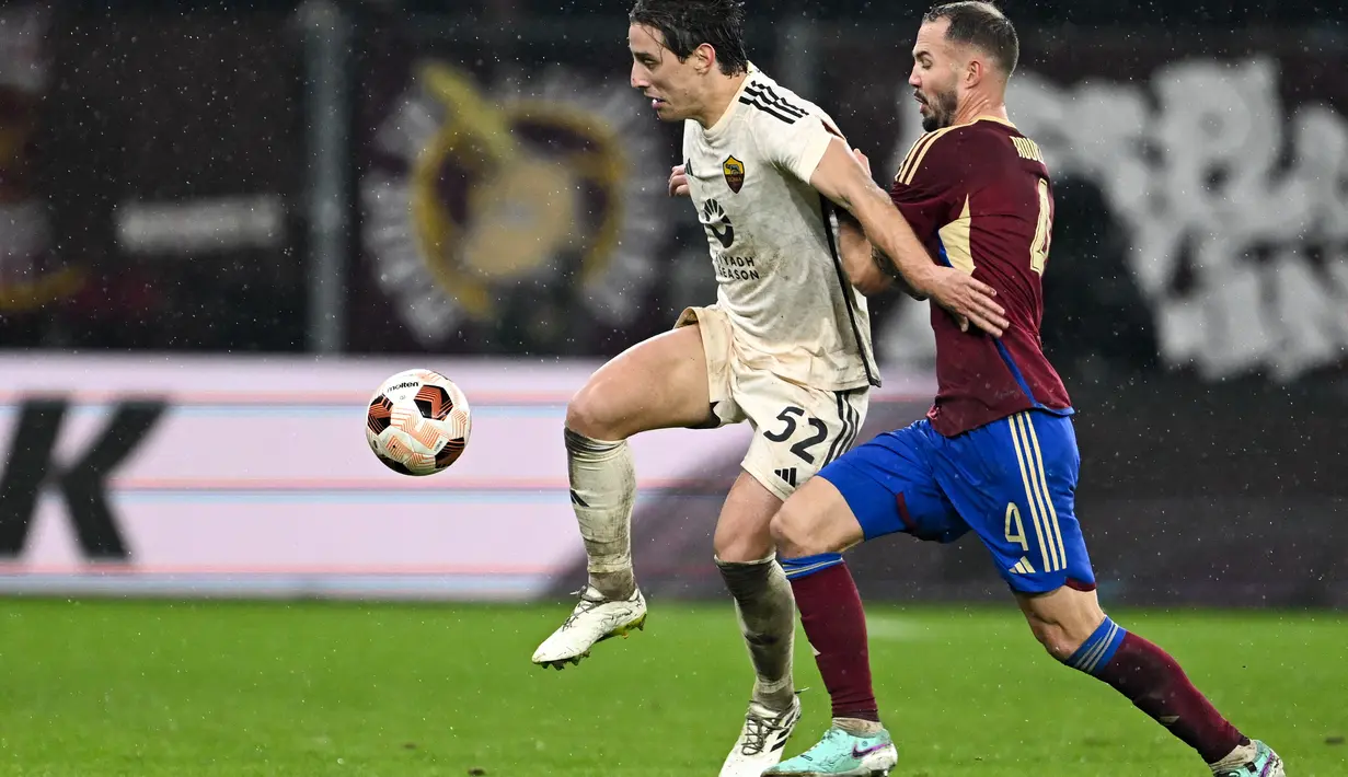 Gelandang AS Roma #52 Edoardo Bove (Kiri) bersaing dengan bek FC Servette #4 Steve Rouiller (kanan) pada laga matchday 5 Grup G Liga Europa 2023/2024 di Stade de Geneve, Jumat (1/12/2023) dini hari WIB. (Fabrice COFFRINI / AFP)