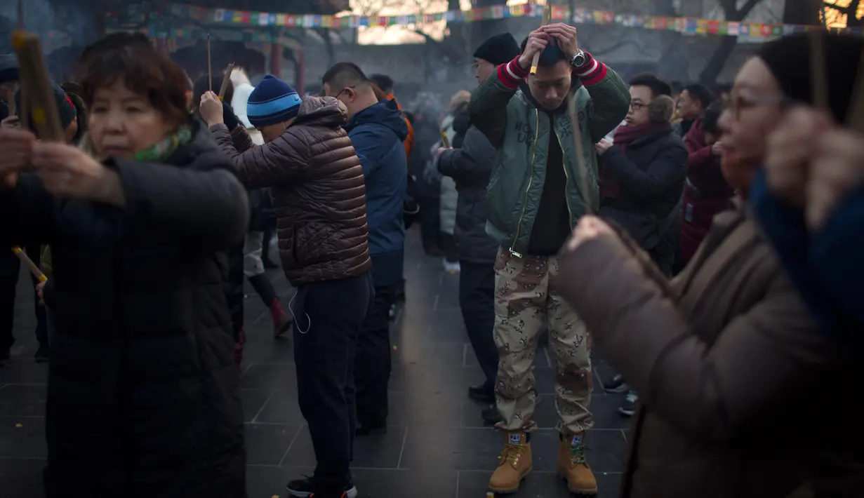 Orang-orang memegang dupa saat berdoa di Kuil Lama di Beijing (5/2). Orang-orang China merayakan hari pertama Tahun Baru Imlek pada hari Selasa, Tahun Babi di zodiak Tiongkok dengan berdoa di kuil. (AP Photo/Mark Schiefelbein)
