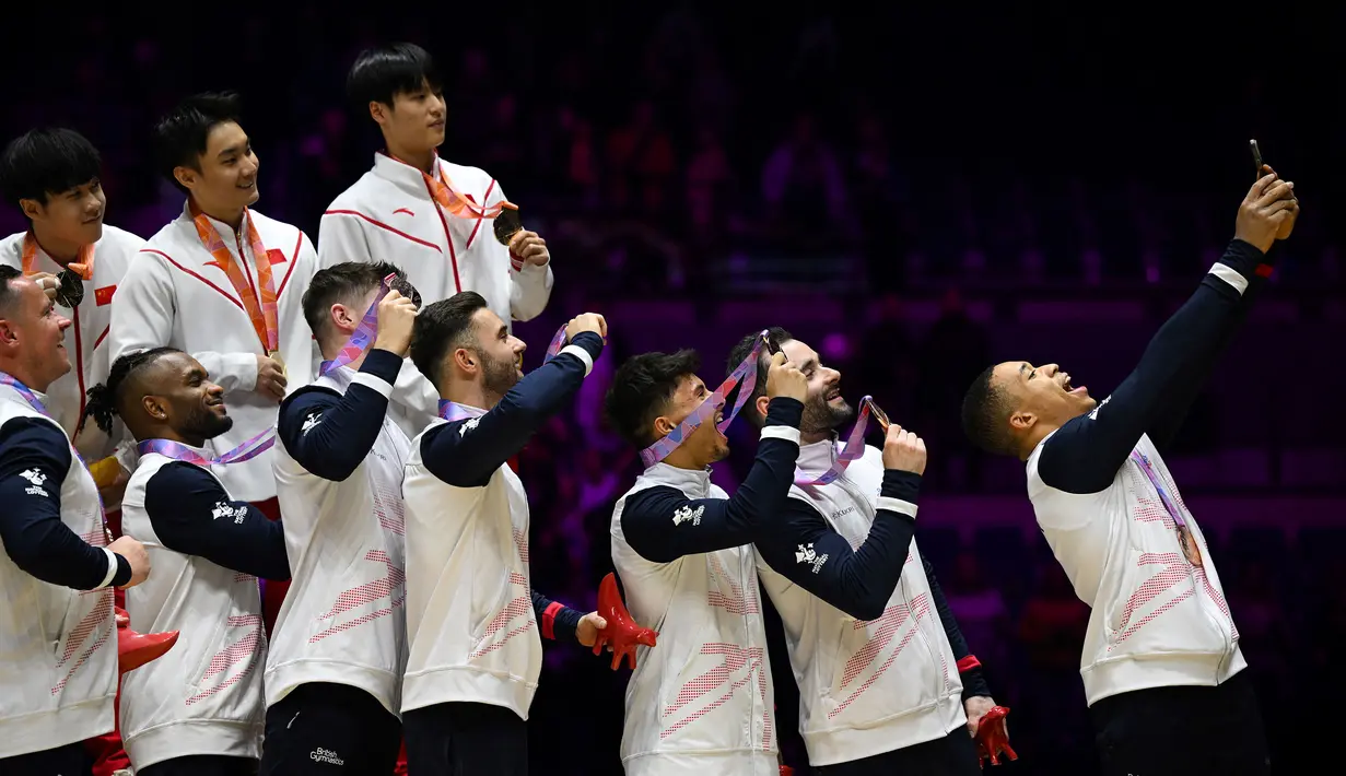 Pesenam Inggris, Joe Fraser (kanan) melakukan swafoto bersama dengan rekan setim dan pesaingnya saat mereka merayakan podium setelah bertanding dalam acara final beregu putra Kejuaraan Dunia Senam Artistik 2022 di Liverpool, Inggris, pada 2 November 2022. (AFP/Paul Ellis)