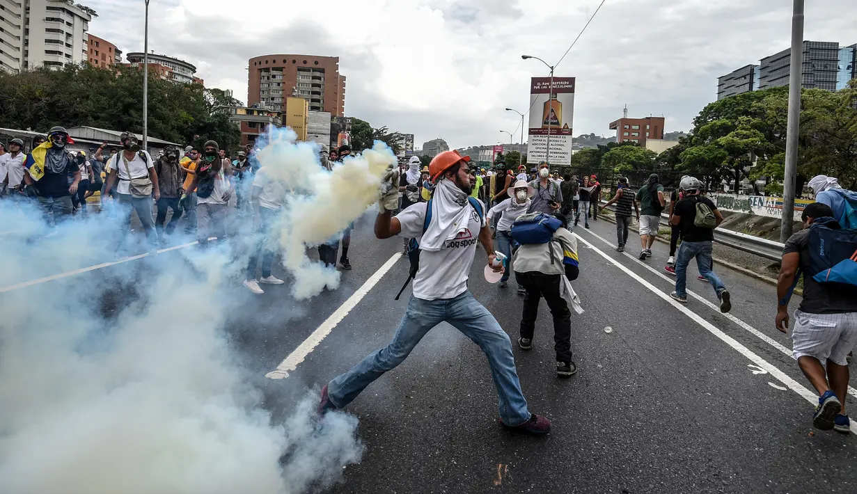 Demonstran melempar gas air mata yang telah ditembakkan polisi saat aksi menentang Presiden Venezuela Nicolas Maduro di Caracas, kamis (20/4). Tiga orang dikabarkan tewas dalam aksi demonstrasi tersebut.  (AFP PHOTO/ Juan BARRETO)