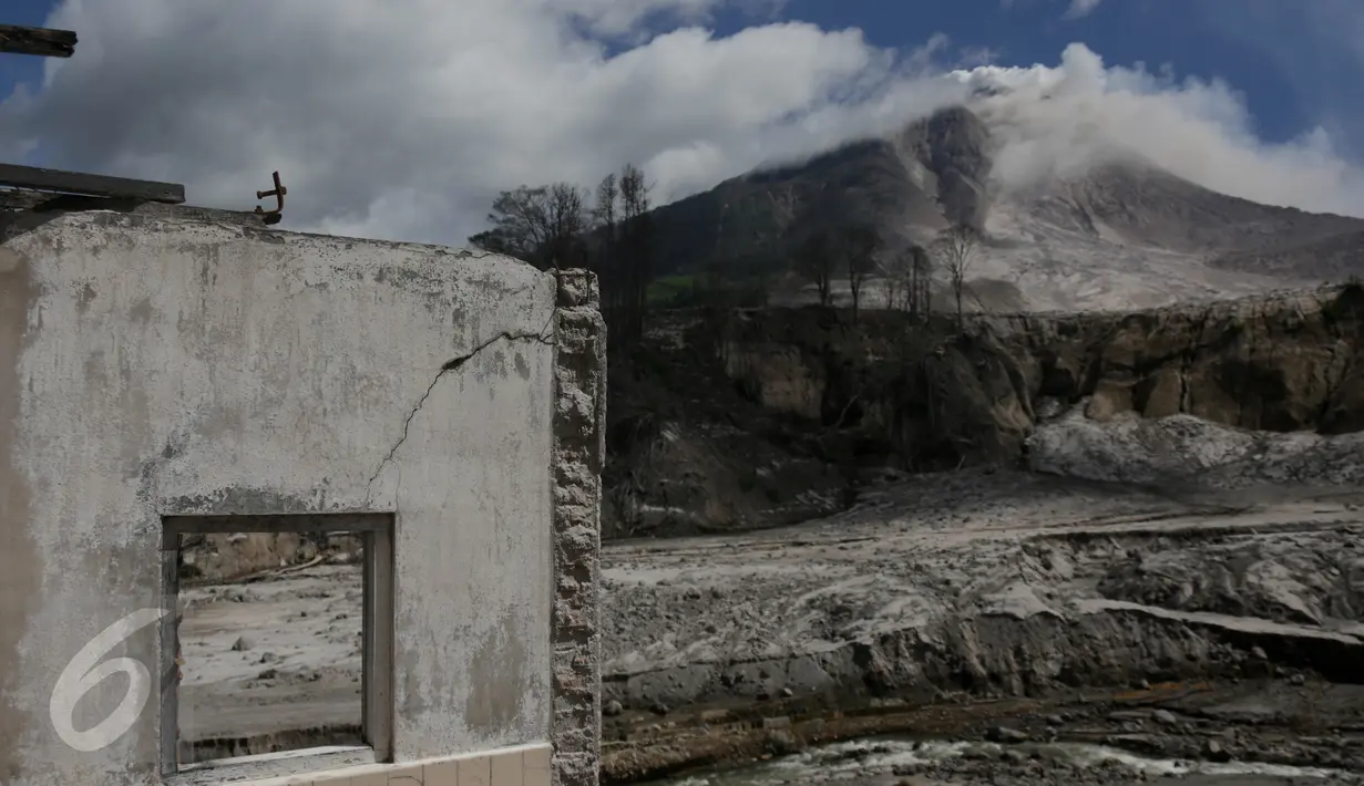 Gunung Sinabung terlihat dari puing rumah yang rusak akibat luncuran awan panas pada April 2015 di Desa Sibintun, Karo, Sumatera Utara, Minggu (5/7/2015). Akibat letusan Sinabung, desa tersebut sudah tak lagi berbentuk. (Liputan6.com/Johan Tallo)