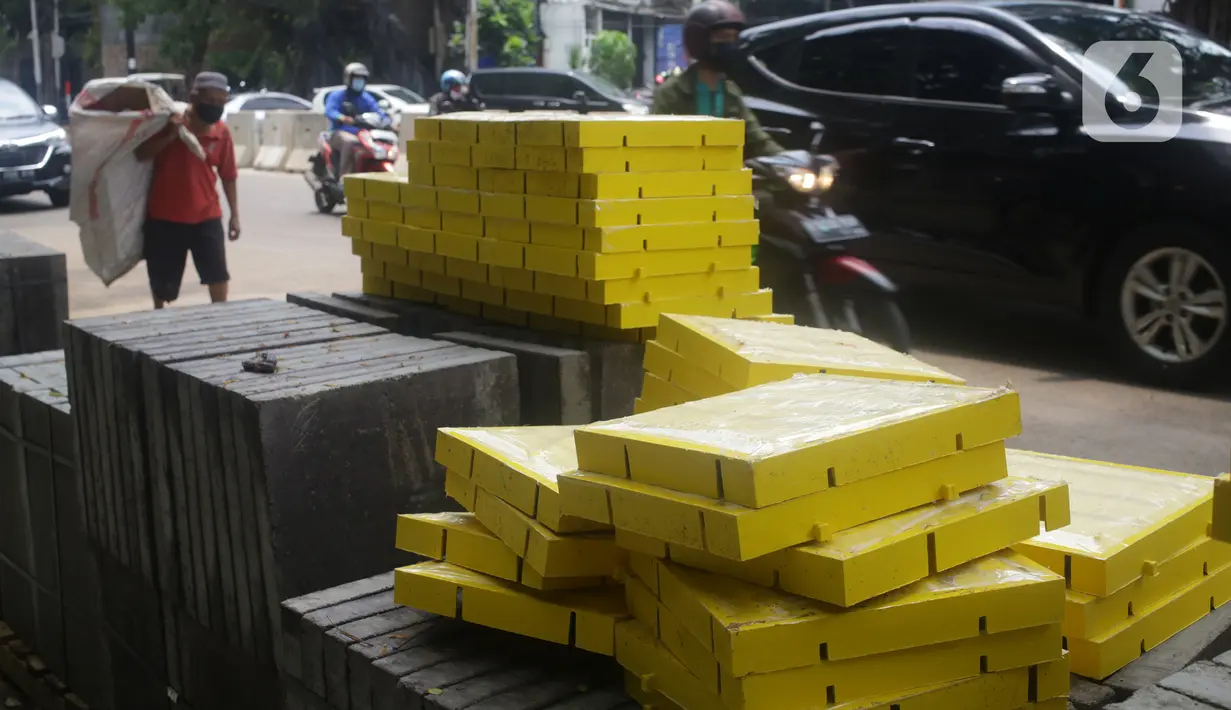 Kendaraan melintas di samping proyek revitalisasi trotoar di kawasan Senopati, Kebayoran Baru, Jakarta, Rabu (15/9/2021). Sepanjang 2018-2020, Pemprov DKI telah membangun trotoar seluas 760.305 meter persegi di 5 wilayah DKI Jakarta. (Liputan6.com/Herman Zakharia)