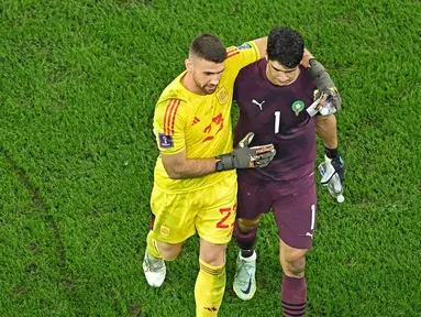 Kiper Spanyol, Unai Simon sempat saling berbincang dengan kiper Maroko, Yassine Bounou, sebelum babak adu penalti pada laga 16 besar Piala Dunia 2022 di Stadion Education City, Selasa (6/12/2022). (AFP/Manan Vatsyayana)