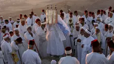 Pendeta Samaria mengangkat sebuah gulungan Taurat dalam upacara tradisional perayaan Festival Shavuot di Gunung Gerizim, Tepi Barat, Minggu (28/6/2020). Hari Raya Shavuot adalah untuk memperingati hari Allah memberikan Taurat kepada Musa dan bangsa Israel di Gunung Sinai. (Xinhua/Ayman Nobani)