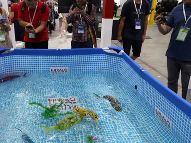 Pengunjung melihat ikan robot buatan Hiwao saat China International Robot Show di Shanghai (10/7/2019). Pameran yang menghadirkan robot-robot canggih ini diselenggarakan dari 10 sampai 13 Juli 2019. (AFP Photo/STR)