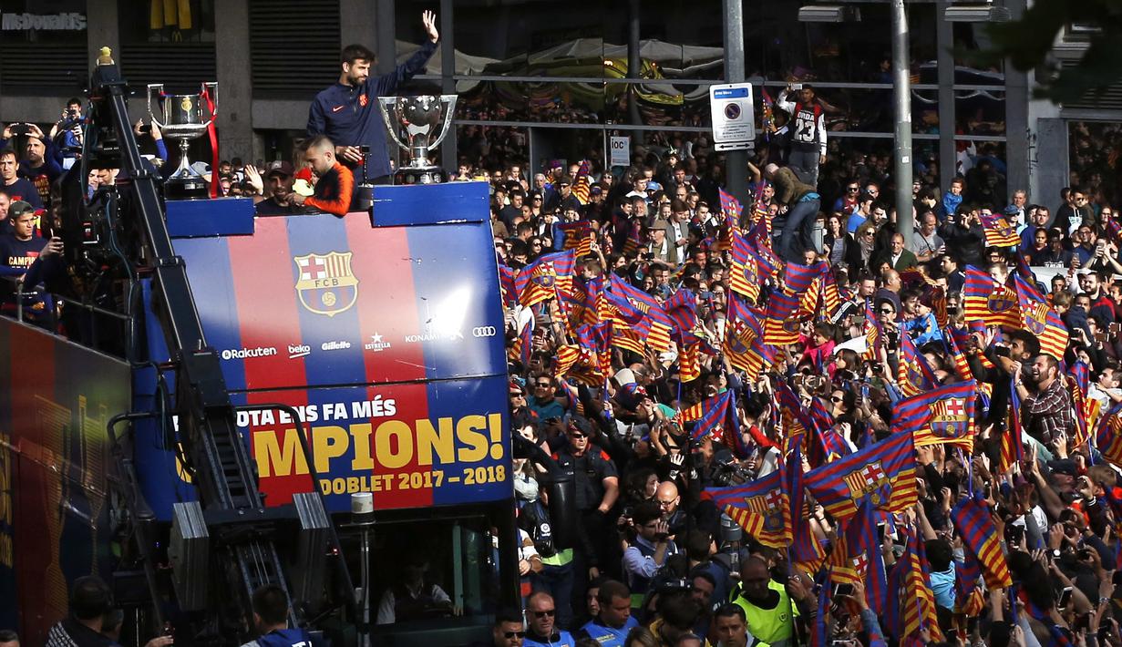 Pemain Barcelona, Gerard Pique memberikan salam kepada fans saat parade juara di Barcelona, (30/4/2018). Barcelona memastikan Gelar La Liga 2017-2018 usai kalahkan Deportivo 4-2. (AP/Manu Fernandez)