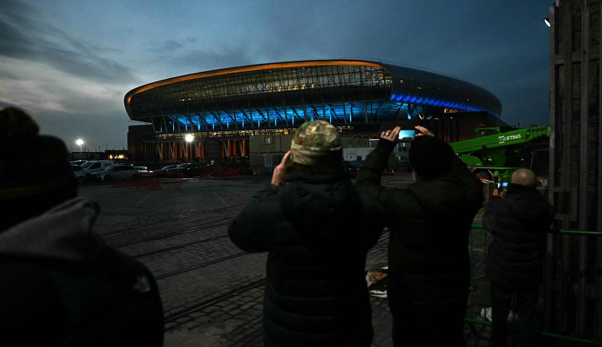 Para fans memotret stadion baru Everton, Bramley Moore Dock menjelang pertandingan uji coba persahabatan antara Everton U18 melawan Wigan U18 di Liverpool, Inggris, Senin (17/02/2025) waktu setempat. (AFP/Paul Ellis)