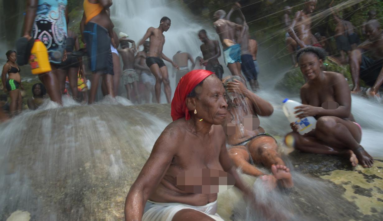 Sejumlah wanita bertelanjang dada mandi di bawah air terjun di Saut d' Eau, Haiti (15/7). Ini merupakan ritual tahunan untuk menyembuhkan penyakit dan mensucikan diri. (AFP Photo/Hektor Retamal)