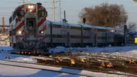 Sebuah kereta komuter melaju menuju pusat kota Chicago ketika api menyala di sepanjang rel di dekat stasiun Metra Western Avenue, 29 Januari 2019. Metra memakai sistem pemanas berbahan bakar gas untuk menghangatkan lintasan yang dingin. (AP/Kiichiro Sato)