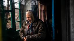 Seorang wanita berdiri di rumahnya dengan jendela yang rusak setelah penembakan di Chasiv Yar, dekat Bakhmut pada 28 Februari 2023. Presiden Ukraina Volodymyr Zelensky mengatakan situasi di kota Bakhmut, di garis depan timur menjadi semakin sulit setalah pasukan Rusia berusaha merebut kota itu selama lebih dari enam bulan. (Dimitar DILKOFF/AFP)