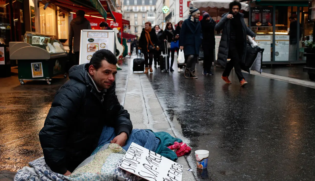 Seorang tunawisma duduk di jalan-jalan di Paris, Prancis, Senin (5/2). (AP Photo / Francois Mori)
