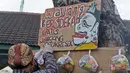 Seniman wayang uwuh, Iskandar Hardjodimuljo menggantungkan paket bahan makanan di jalan Cawang Baru Utara, Jakarta, Sabtu (18/4/2020). Paket bahan makanan yang diberi nama "Wayang Bersedekah" tersebut membantu warga yang kesulitan akibat dampak pandemi covid-19. (Liputan6.com/Herman Zakharia)