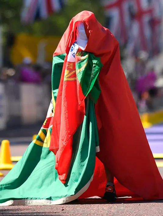 Pelari putri asal Portugal, Ines Henriques menutup tubuhnya dengan bendera negaranya setelah memenangkan medali emas dalam lomba lari putri selama Kejuaraan Atletik Dunia di London, Inggris (13/8). (AP Photo / Martin Meissner)