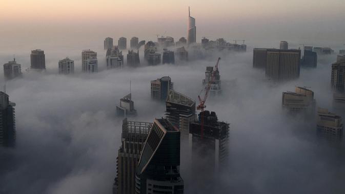 Saat gedung-gedung pencakar langit di selimuti kabut pagi di Kota Dubai, Uni Emirat Arab, Senin (5/12). Kota Dubai, terkenal dengan bangunan-bangunan mewah pencakar langit. Satu di antaranya adalah yang tertinggi di dunia, Burj Khalifa. (AFP/Rene Slama)