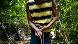 Abdul Samad Ahmad mengikat tali sebelum mengambil madu di hutan Ulu Muda di Sik, Malaysia (11/3). Pada malam hari di hutan Malaysia, dua pemburu madu berada di dahan pohon menggunakan obor untuk menarik ribuan lebah. (AFP Photo/Manan Vatsyayana)