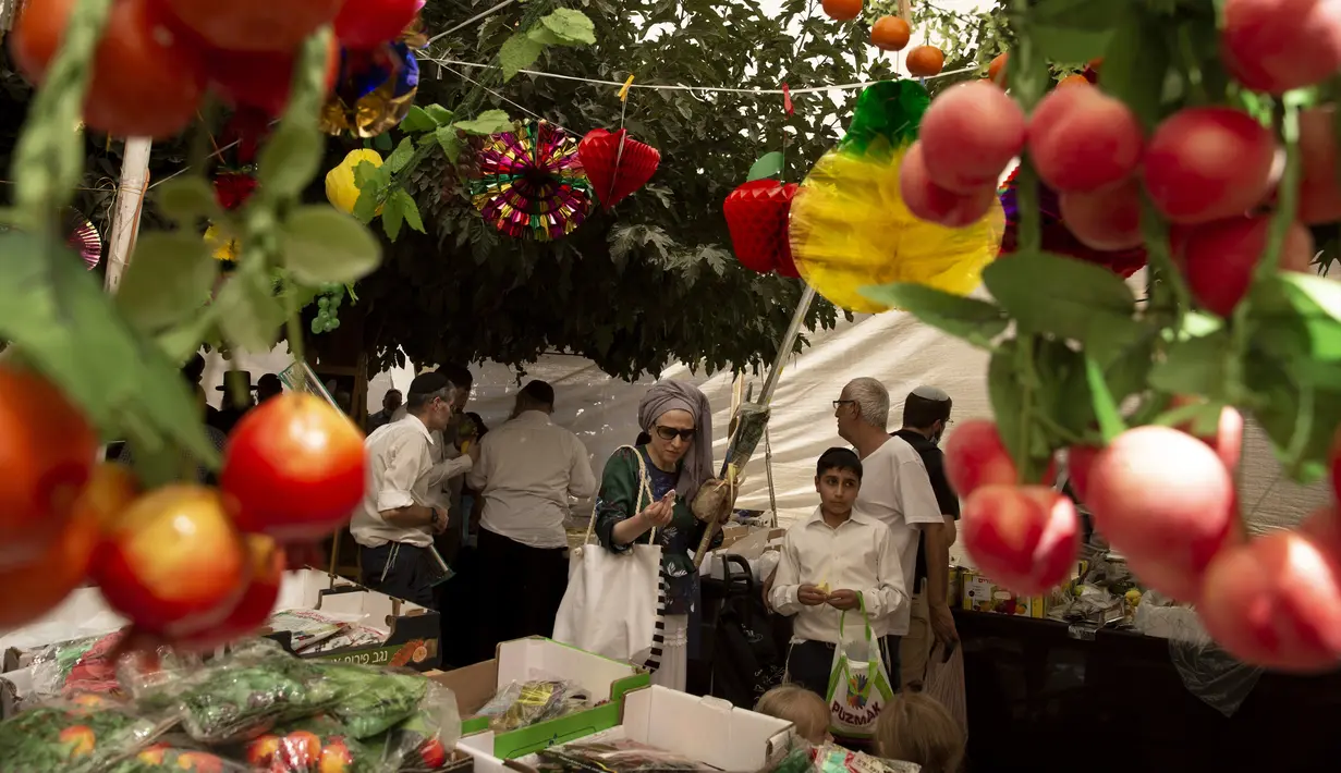 Umat Yahudi berbelanja barang-barang yang akan digunakan dalam ritual Hari Raya Sukkot di Yerusalem, 20 September 2021. Tenda tempat mereka berbelanja didirikan di seberang Pasar Mahane Yehuda yang diperuntukkan bagi pemegang Green Pass yang sudah divaksinasi COVID-19. (AP Photo/Maya Alleruzzo)