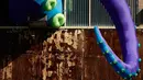 Sebuah patung karet berjudul "Sea Monsters HERE" menghiasi gudang berkarat Building 61 di Navy Yard di Philadelphia, Selasa (9/10). Kreasi sepanjang 40 kaki ini menampilkan tentakel ungu besar yang keluar dari jendela hingga ke atap. (AP/Matt Rourke)