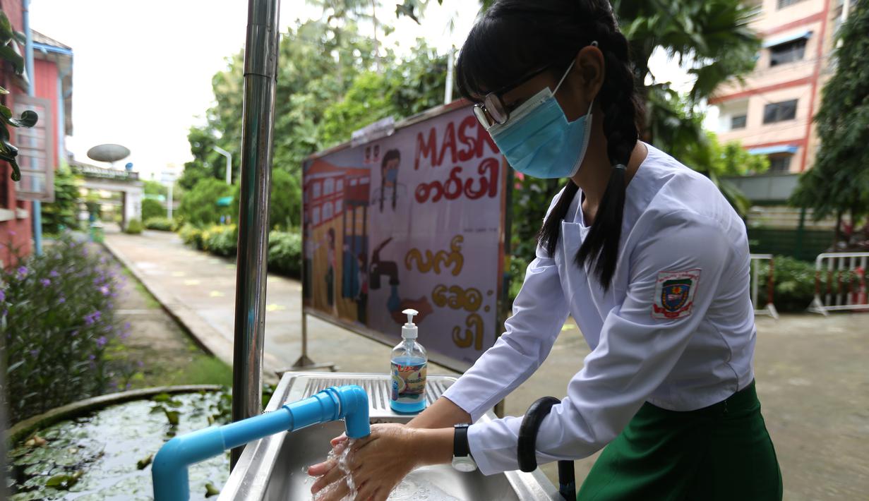 Seorang siswa yang mengenakan masker mencuci tangan di sekolah pada hari pendaftaran sekolah di Yangon, Myanmar (13/7/2020). Myanmar sejak Selasa (7/7) memulai pendaftaran sekolah untuk tahun ajaran 2020-2021, yang tertunda akibat pandemi COVID-19. (Xinhua/U Aung)